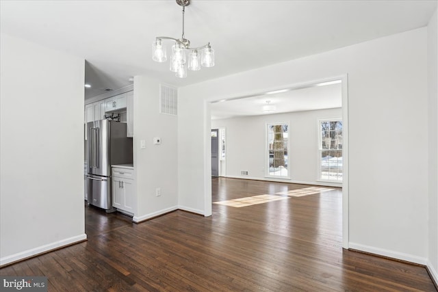 unfurnished dining area featuring dark wood-type flooring and a notable chandelier