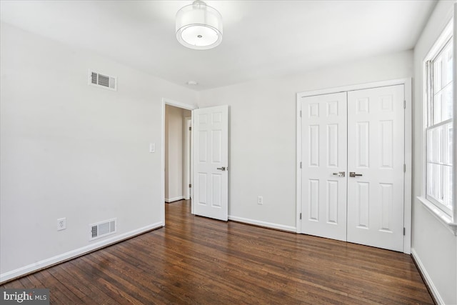 unfurnished bedroom with a closet and dark hardwood / wood-style floors