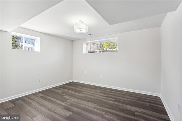 basement with plenty of natural light and dark wood-type flooring