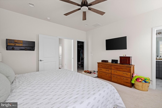 carpeted bedroom with ensuite bath, a spacious closet, a closet, and ceiling fan