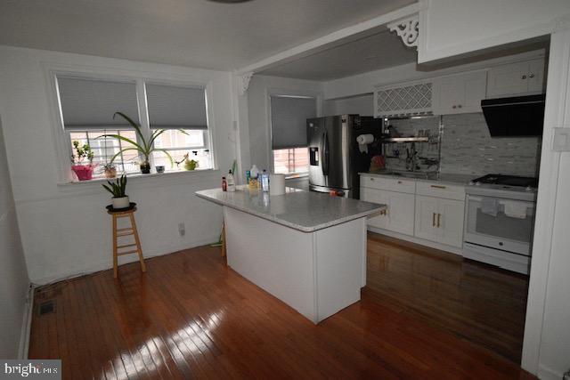 kitchen featuring white cabinets, stainless steel refrigerator with ice dispenser, white range with electric stovetop, a kitchen island, and extractor fan