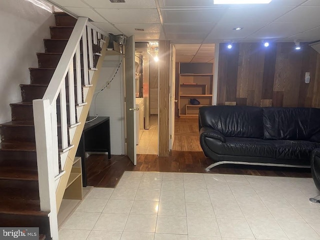 basement featuring a paneled ceiling and light hardwood / wood-style floors