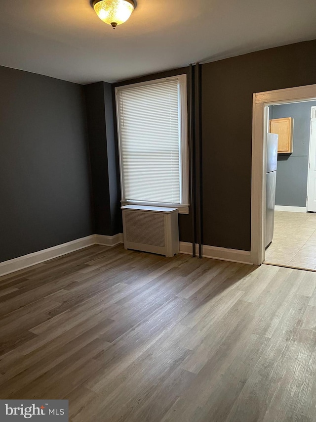 empty room featuring radiator heating unit and light hardwood / wood-style flooring