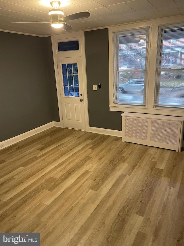 foyer with ceiling fan, radiator heating unit, crown molding, and hardwood / wood-style flooring