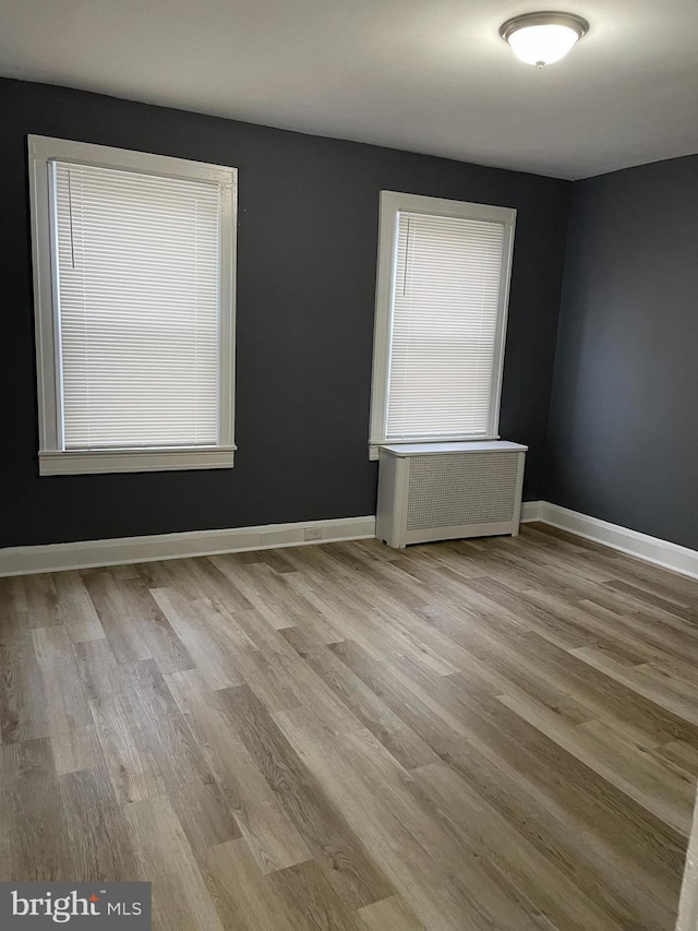 unfurnished room with radiator heating unit and light hardwood / wood-style flooring