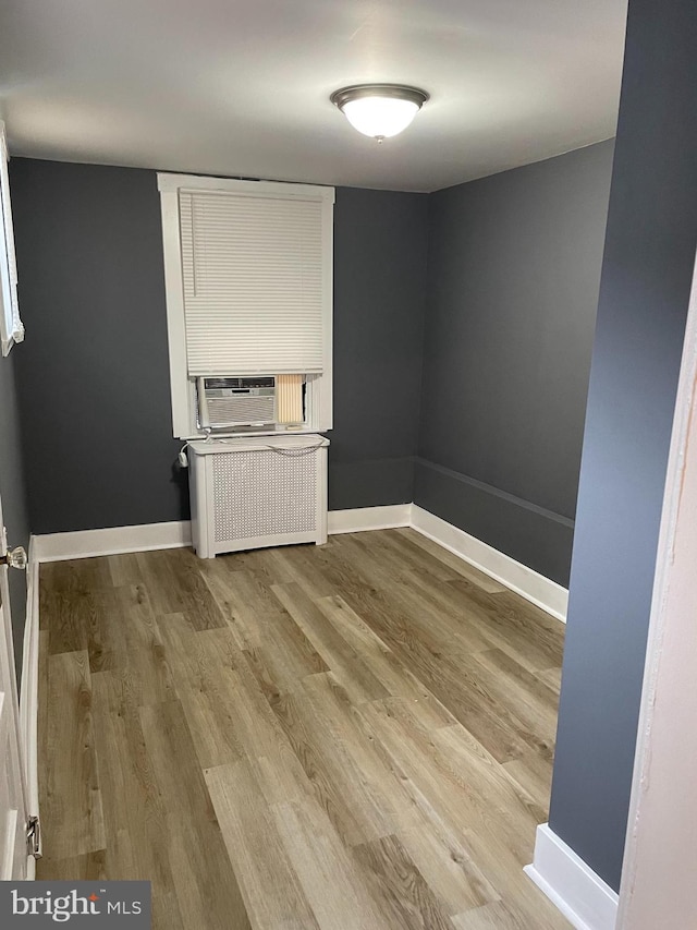 spare room featuring hardwood / wood-style floors, cooling unit, and radiator heating unit