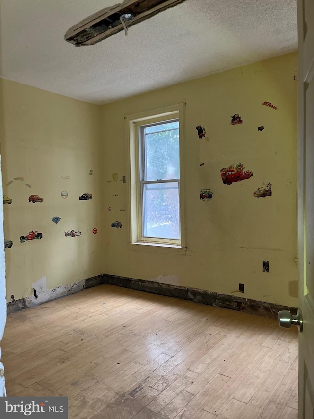 unfurnished room featuring light hardwood / wood-style flooring and a textured ceiling