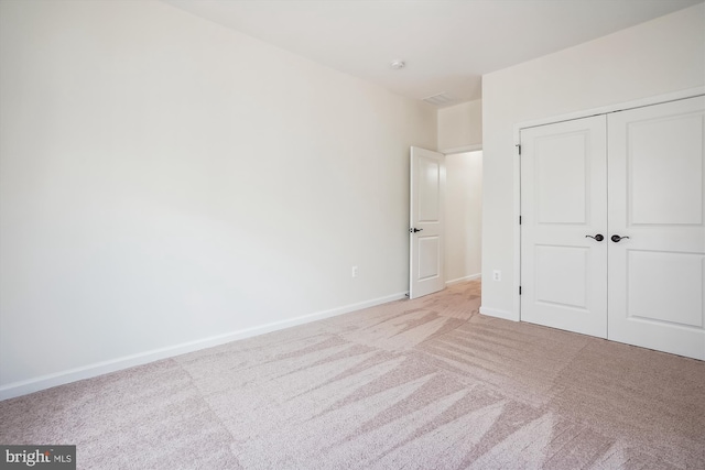 unfurnished bedroom featuring light colored carpet and a closet