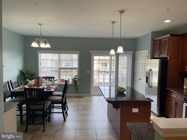 kitchen with an inviting chandelier, a kitchen breakfast bar, hanging light fixtures, stainless steel fridge, and light tile patterned floors