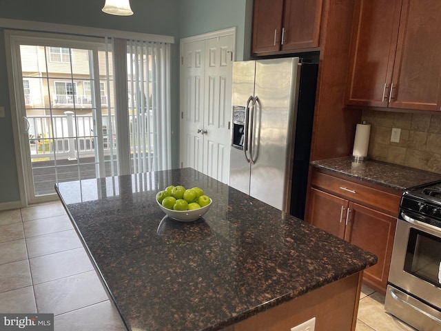 kitchen featuring backsplash, dark stone countertops, a center island, and appliances with stainless steel finishes