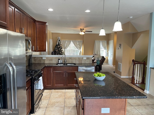 kitchen featuring sink, ceiling fan, decorative backsplash, a kitchen island, and stainless steel appliances