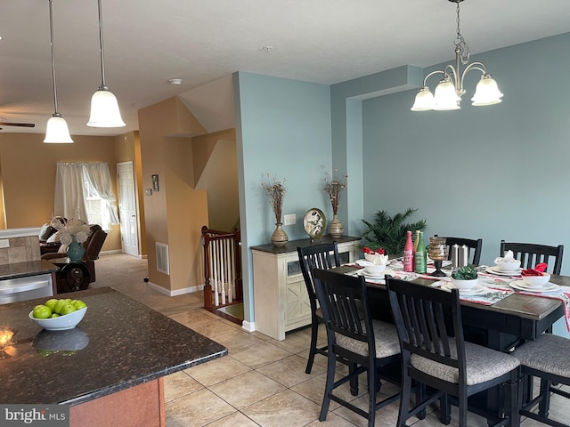 tiled dining space with ceiling fan with notable chandelier