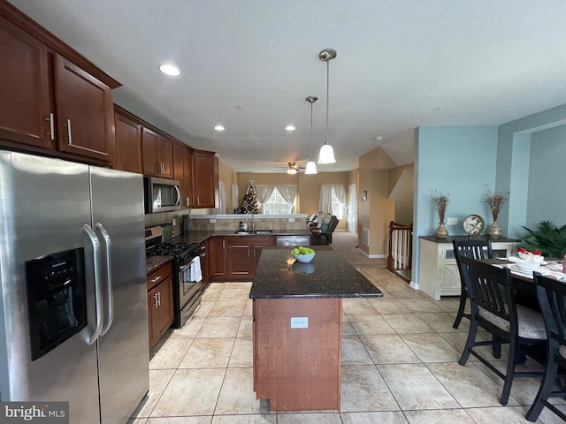 kitchen featuring appliances with stainless steel finishes, ceiling fan, dark stone countertops, a kitchen island, and light tile patterned flooring