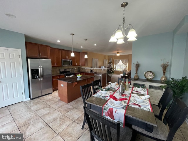 dining room with sink, light tile patterned floors, and ceiling fan with notable chandelier