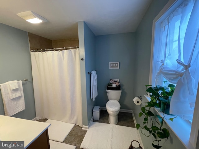 bathroom featuring tile patterned floors, toilet, vanity, and walk in shower