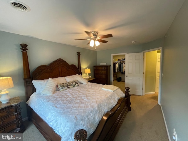 carpeted bedroom featuring a walk in closet, a closet, and ceiling fan