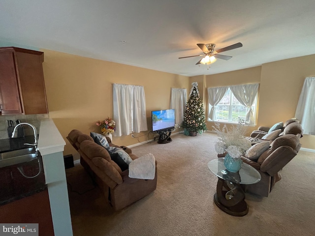 carpeted living room featuring ceiling fan and sink