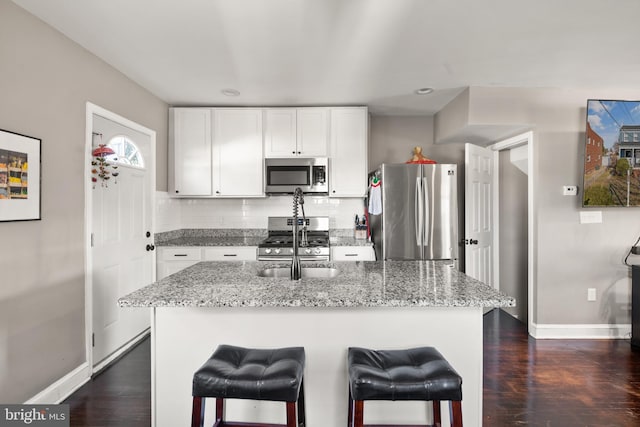 kitchen with white cabinetry, dark wood-type flooring, a kitchen island with sink, and appliances with stainless steel finishes