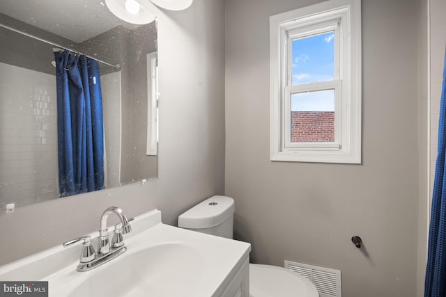 bathroom featuring vanity, toilet, and walk in shower