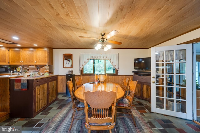 dining area with sink, ceiling fan, wooden walls, and wood ceiling