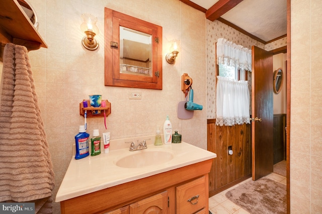 bathroom featuring beam ceiling, vanity, tile walls, and ornamental molding