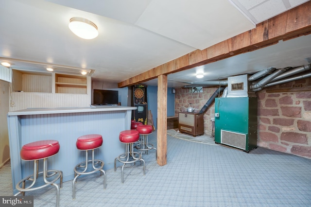 kitchen with a kitchen breakfast bar, kitchen peninsula, heating unit, and brick wall