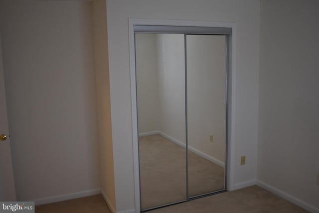 unfurnished bedroom with light colored carpet and a closet