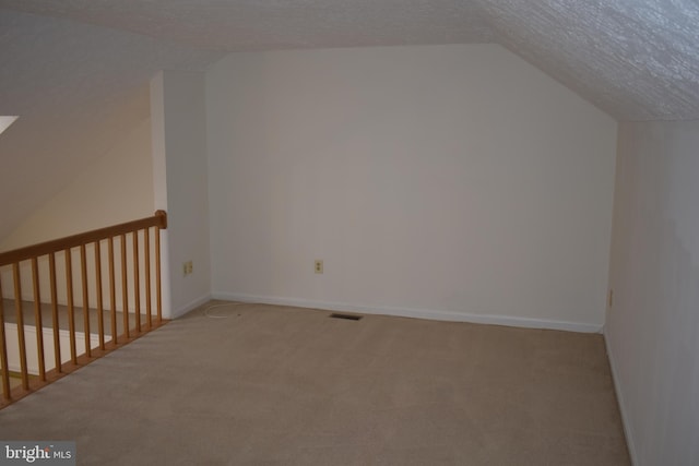 additional living space with carpet, a textured ceiling, and vaulted ceiling