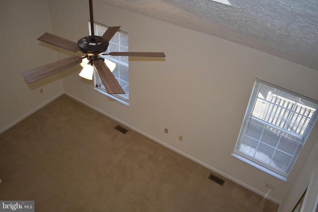 unfurnished room featuring ceiling fan, carpet floors, and a textured ceiling