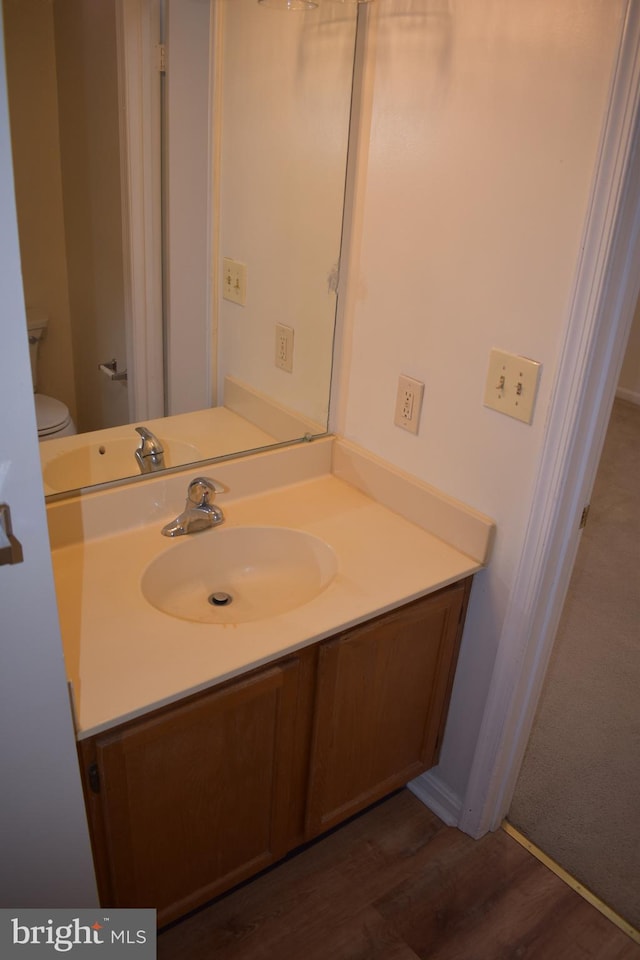 bathroom with hardwood / wood-style floors, vanity, and toilet