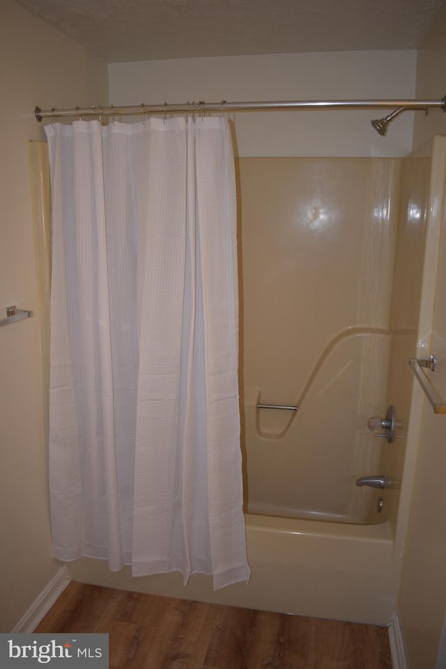 bathroom with wood-type flooring and shower / bath combination with curtain