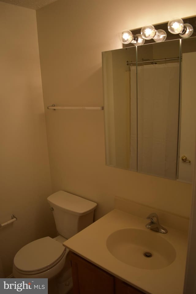 bathroom featuring vanity, toilet, and walk in shower