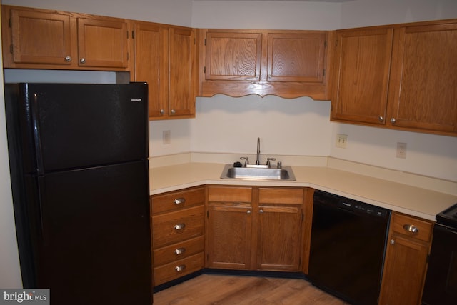 kitchen with black appliances, light hardwood / wood-style floors, and sink