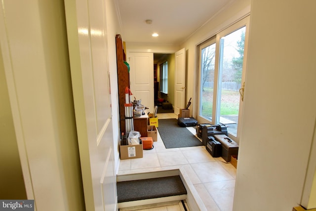 corridor with crown molding, plenty of natural light, and light tile patterned floors