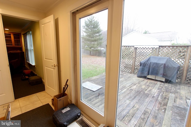 doorway with crown molding and light tile patterned flooring