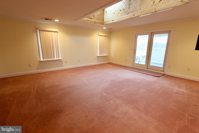 spare room featuring carpet floors, a skylight, and ornamental molding