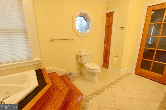 bathroom with tile patterned flooring, tiled bath, and toilet