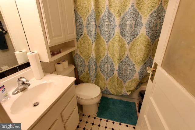 bathroom with vanity, tasteful backsplash, toilet, and walk in shower