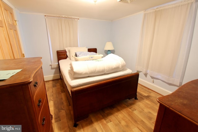 bedroom with crown molding and light hardwood / wood-style flooring