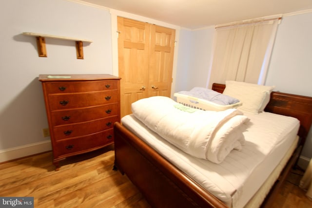 bedroom featuring light hardwood / wood-style flooring, a closet, and ornamental molding