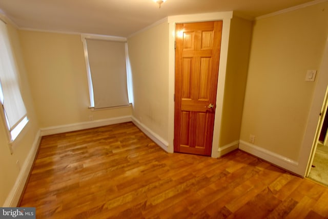 empty room featuring wood-type flooring and ornamental molding