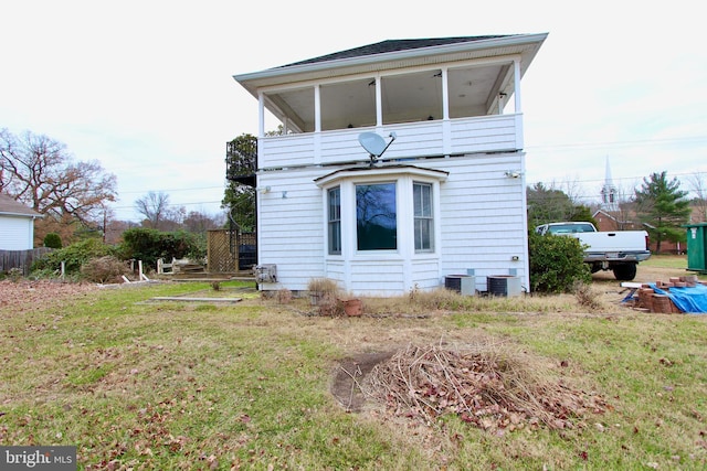 rear view of house featuring a balcony, central AC, and a lawn