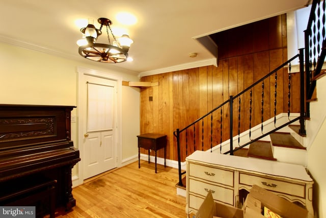 interior space featuring a chandelier, wood walls, ornamental molding, and light hardwood / wood-style flooring