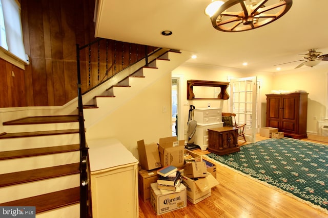 staircase featuring ceiling fan, wood-type flooring, and ornamental molding