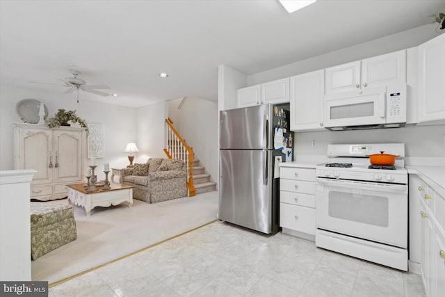 kitchen featuring ceiling fan, white cabinets, light colored carpet, and white appliances