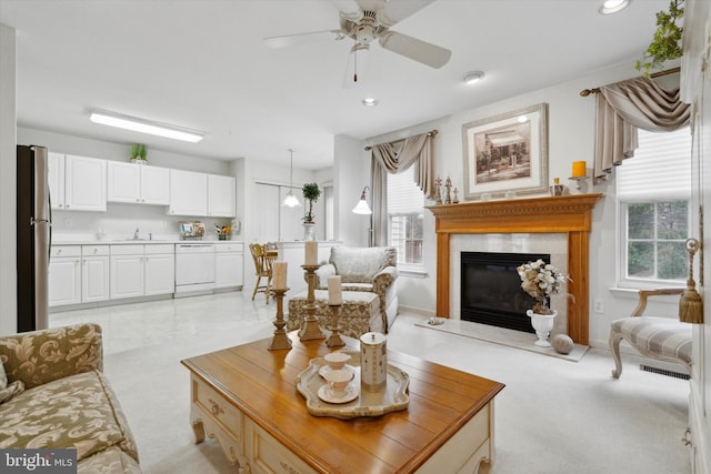 living room with ceiling fan, sink, and light carpet