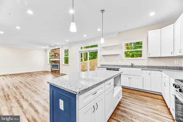 kitchen with white cabinets, a kitchen island, hanging light fixtures, and a healthy amount of sunlight