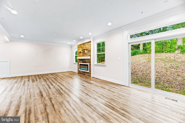 unfurnished living room with a fireplace, crown molding, and light hardwood / wood-style flooring