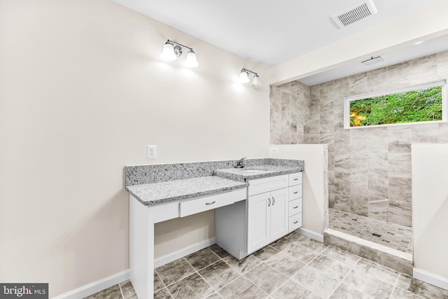 bathroom featuring tiled shower and vanity