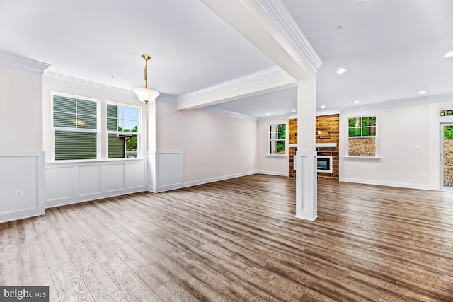 unfurnished living room featuring a fireplace, hardwood / wood-style floors, ornamental molding, and a healthy amount of sunlight